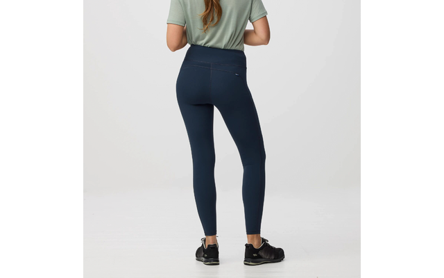 Vista trasera de una persona de pie con camiseta verde, mallas azul oscuro y zapatillas deportivas negras