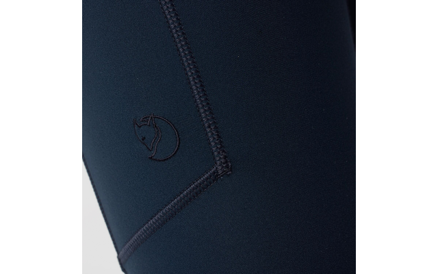 Plano detalle de tela azul oscuro con una costura visible y un logo de zorro bordado