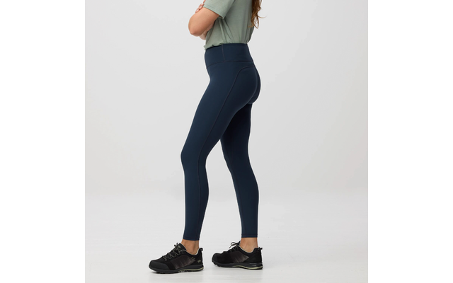 Persona de perfil desde los hombros hasta los pies, con camiseta verde claro, mallas azul oscuro de talle alto y zapatillas deportivas negras sobre fondo claro