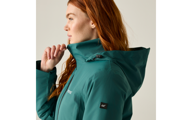 Side profile of a red-haired person with a stud earring wearing a teal hooded jacket and pulling up the collar with one hand