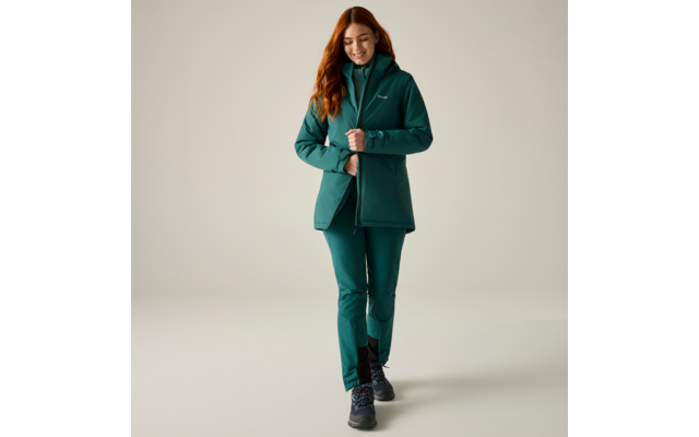 Woman with red hair wearing teal jacket and pants, black lace-up boots, walking forward and smiling