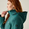 Side profile of a red-haired person with a stud earring wearing a teal hooded jacket and pulling up the collar with one hand