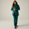 Woman with red hair wearing teal jacket and pants, black lace-up boots, walking forward and smiling