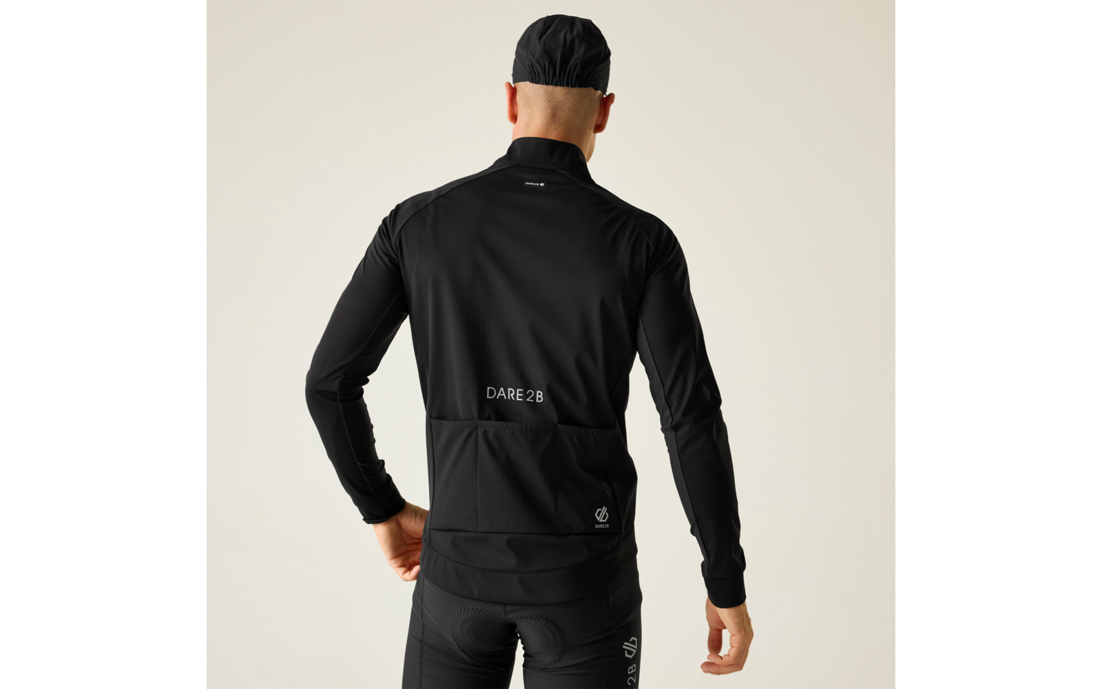 Persona vista da dietro con giacca da ciclismo nera, pantaloni da ciclismo neri e berretto nero su sfondo chiaro