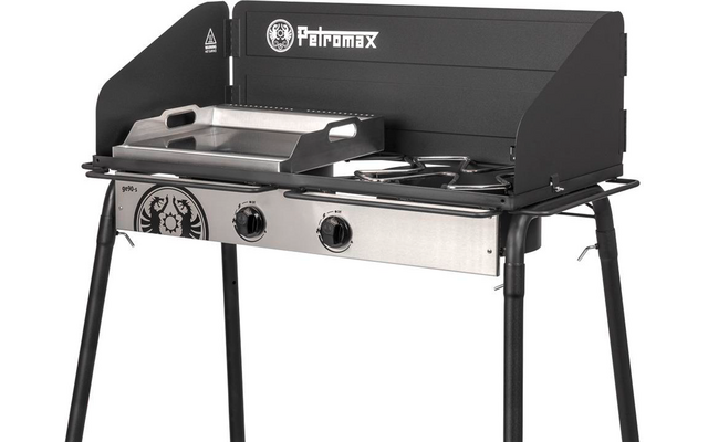 Schwarzer Campinggrill mit Windschutz, Edelstahl-Frontplatte, zwei Drehknöpfe, links flache Grillplatte, rechts zwei runde Brenner, Schriftzug Petromax