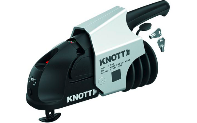 Silver-and-black trailer coupling with 'KNOTT' logo, black handle, black rubber bellows and two metal keys beside it