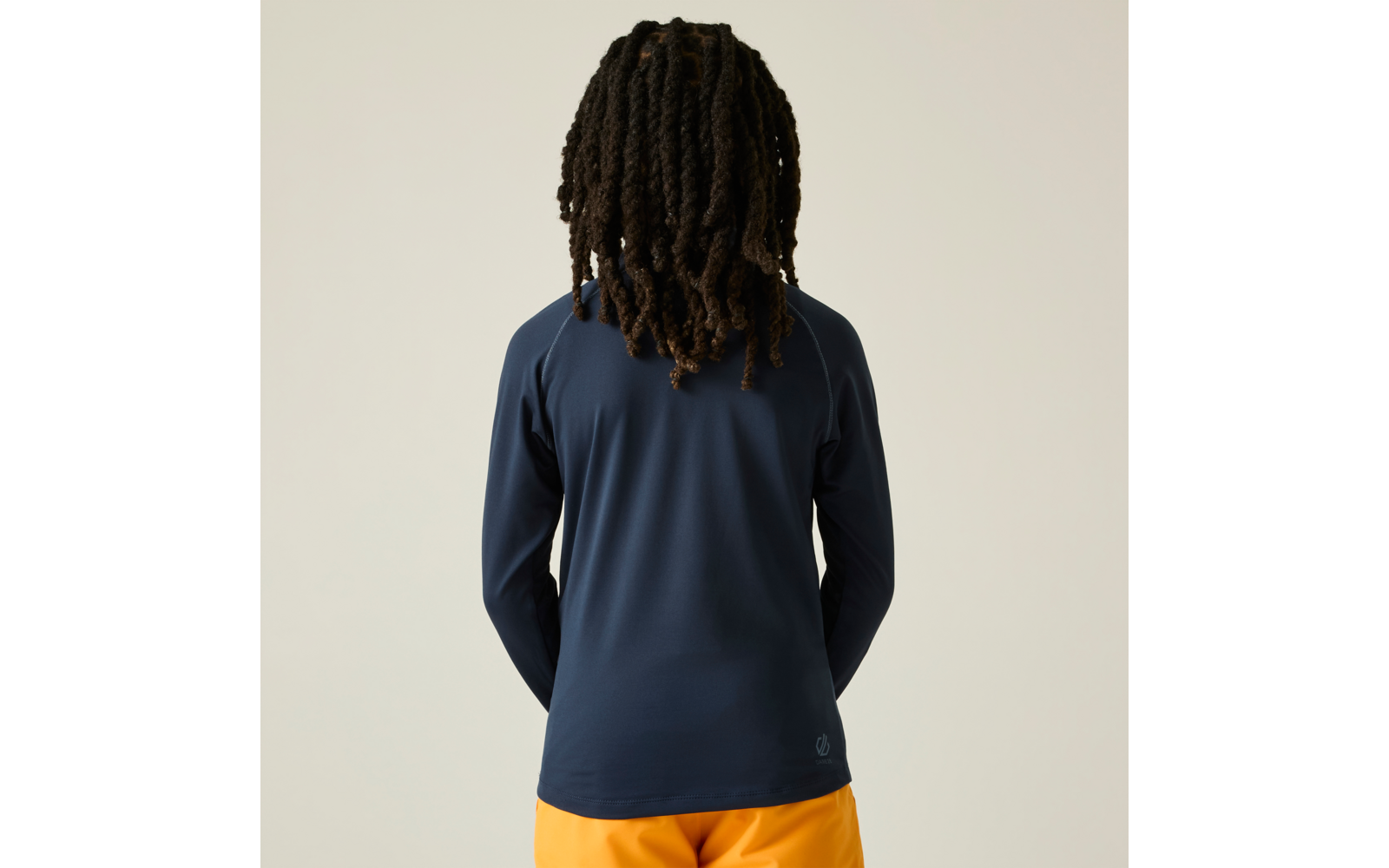 Achteraanzicht van een persoon met dreadlocks die een donkerblauw shirt met lange mouwen en een oranje broek draagt