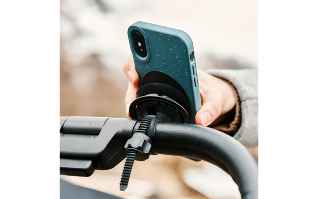 Hand hält Smartphone mit blaugrüner, gesprenkelter Hülle, an einem runden schwarzen Halter am Fahrradlenker befestigt