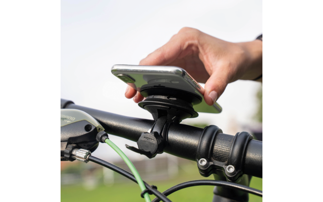 Hand hält Smartphone in einer am Fahrradlenker montierten Halterung; grüne Bremsleitung sichtbar