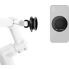 White robotic arm with a black suction-cup gripper on the left; gray smartphone with a round black attachment on the back on the right