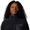 Portrait einer Frau mit lockigen schwarzen Haaren, die einen schwarzen Reißverschluss-Pullover trägt