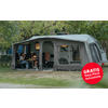 Large gray camping awning with multiple rectangular windows, dark base strip, curtains at the windows, curved roof, guy lines and ground pegs; red round sticker at lower right with white text