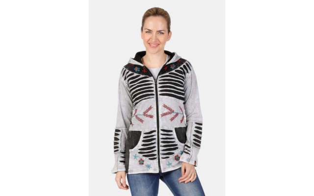Frau vor weißem Hintergrund, trägt graue Jacke mit Reißverschluss, schwarzem Streifenmuster, bunten Stickereien und blaue Jeans