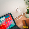 Tablet mit farbigem Bildschirm, das per Kabel an eine Wandsteckdose angeschlossen ist, neben einem Blumentopf