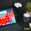 Tablet mit geöffnetem Bildschirm und Tastatur, Ladekabel angeschlossen, neben einer Tasse Kaffee und einer Pflanze