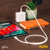 Smartphone mit Apps auf dem Bildschirm, daneben ein orangefarbenes Notizbuch, eine Pflanze in einem weißen Topf und ein weißes Ladegerät mit Kabel