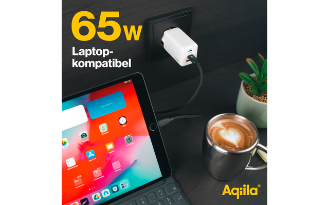 Tablet mit farbigen App-Symbolen, angeschlossenes Ladekabel und Tasse Kaffee neben einem kleinen Pflanzentopf auf dunklem Untergrund