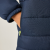Hand in seitlicher Tasche einer dunkelblauen Steppjacke, teilweise geöffneter Reißverschluss mit hellgrünem Zipper