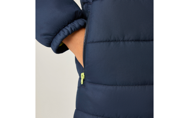 Hand in seitlicher Tasche einer dunkelblauen Steppjacke, teilweise geöffneter Reißverschluss mit hellgrünem Zipper