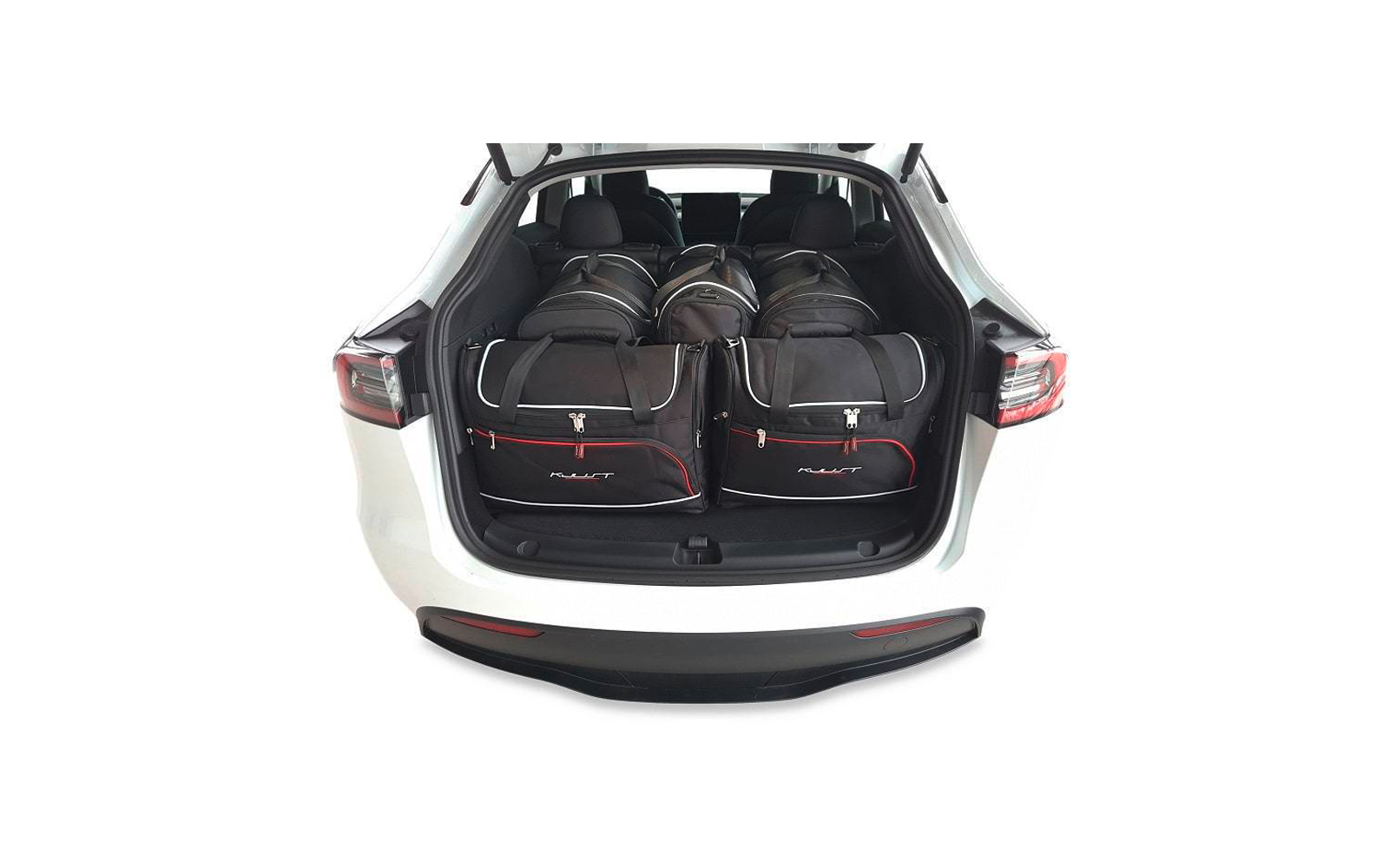 Coffre ouvert d'une voiture blanche contenant cinq sacs de voyage noirs avec anses grises et garniture rouge