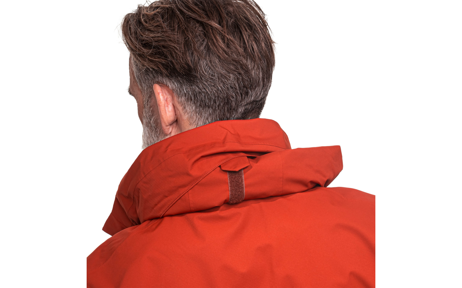Person von hinten mit kurzem dunkelbraunem, leicht ergrautem Haar und roter Jacke mit hohem Kragen vor weißem Hintergrund