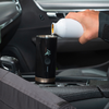 Hand hält einen Autoschlüssel über einem schwarzen Becherhalter in einem Fahrzeug