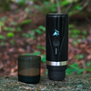 Schwarzer Trinkbecher und schwarze Dose stehen nebeneinander auf einem Stein im Wald