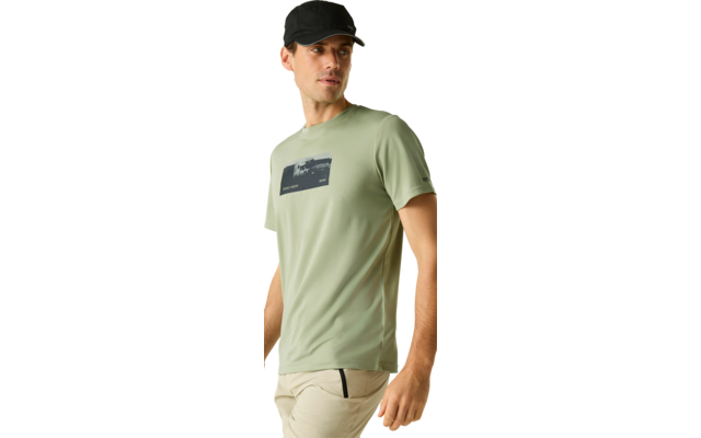 Mann mit schwarzer Baseballkappe, hellgrünem T‑Shirt mit dunklem Brustprint und beigen Hosen, Blick nach links