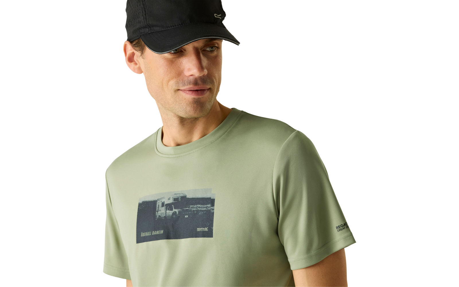 Person mit schwarzer Baseballkappe und hellgrünem T‑Shirt mit dunklem Fotoaufdruck, Blick nach rechts vor hellem einfarbigem Hintergrund