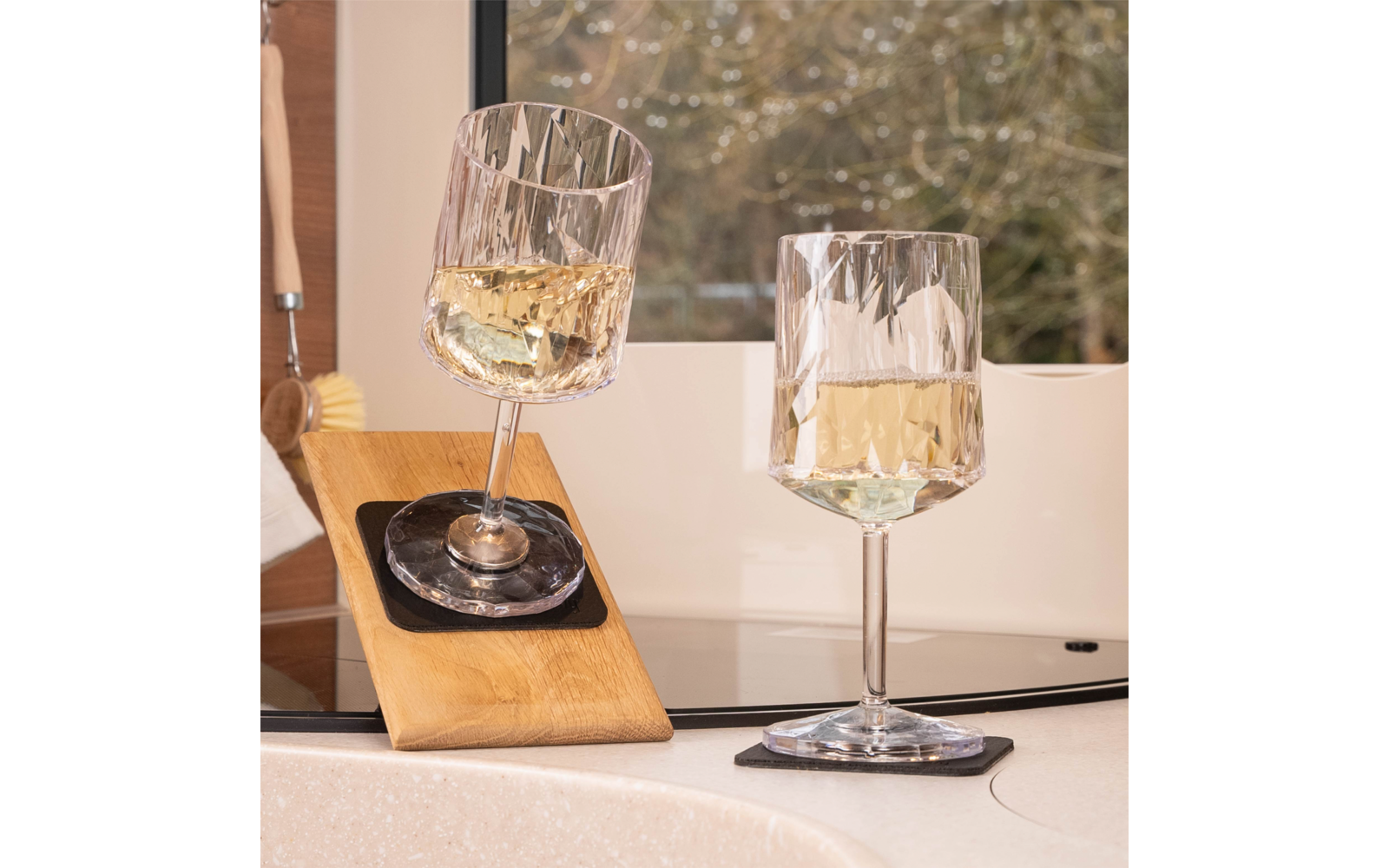 Wine glass with orange-red drink on the deck of a sailboat, trampoline netting, ropes, rigging and open sea in the background
