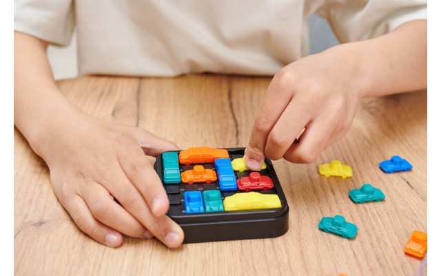 Mains d'enfants jouant avec un jeu de logique coloré sur une table en bois