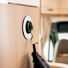Black umbrella hanging on a hook attached to a wooden surface inside a vehicle interior