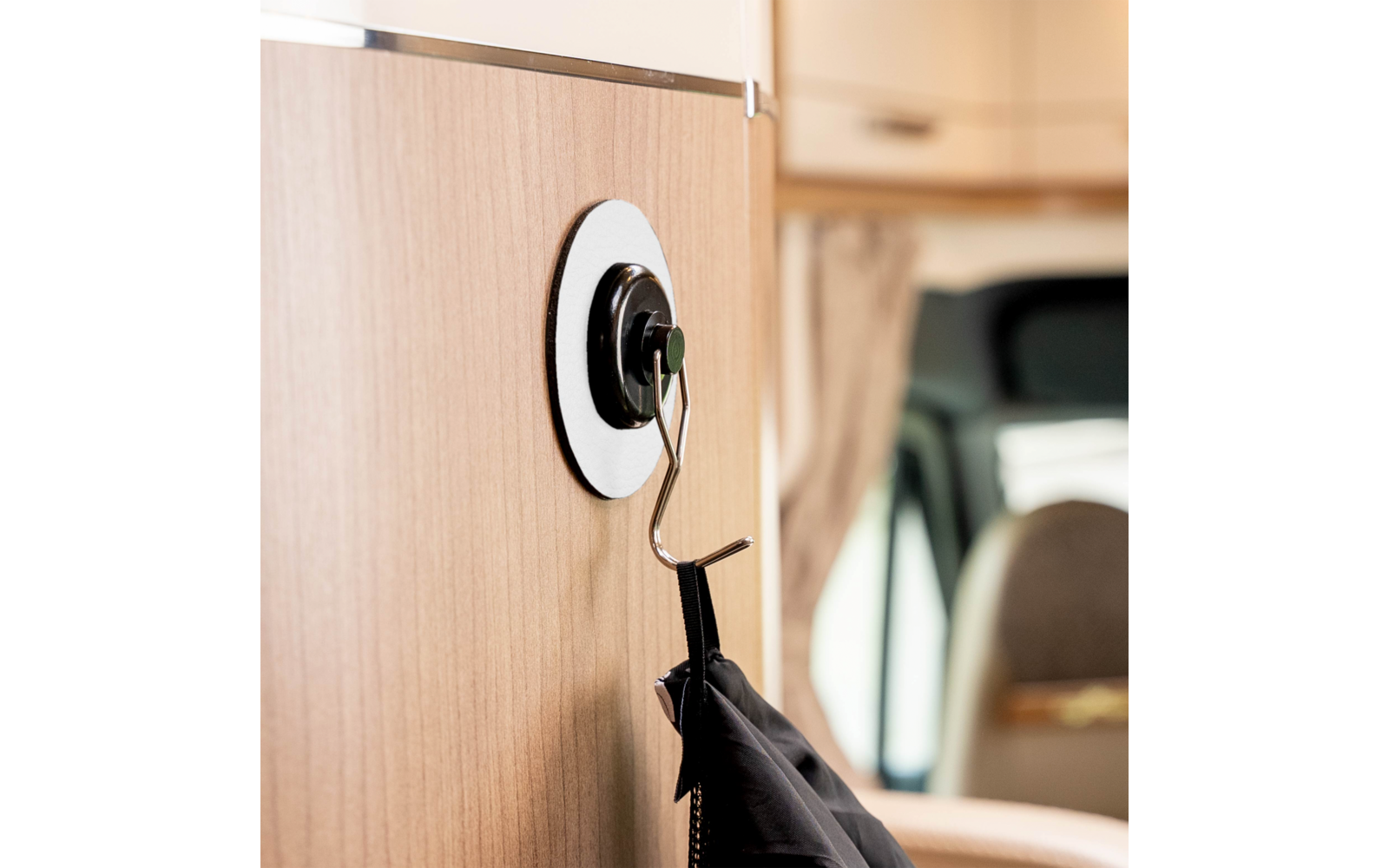 Black umbrella hanging on a hook attached to a wooden surface inside a vehicle interior