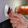 Hand holding and turning a black water tap on a wall