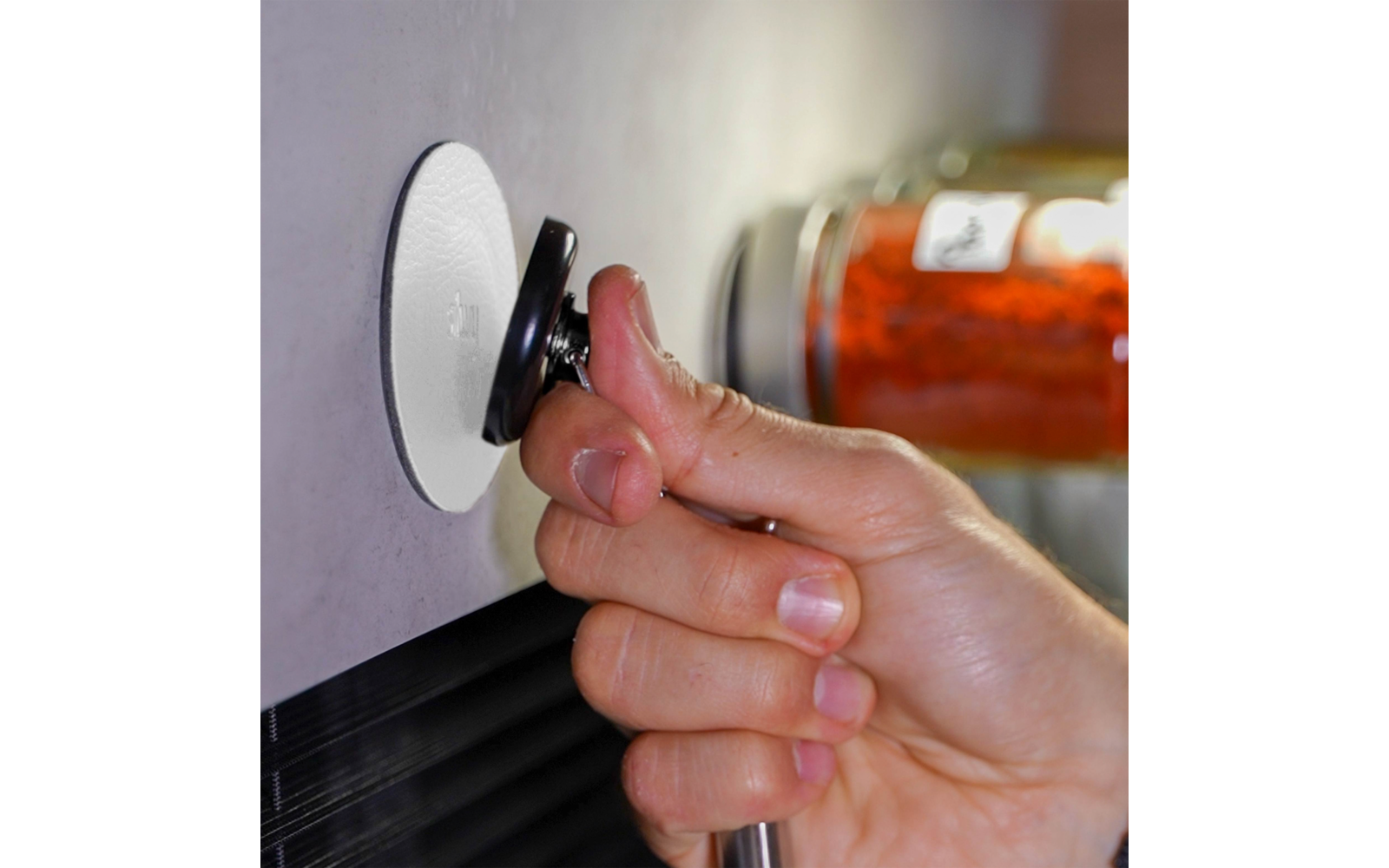 Hand holding and turning a black water tap on a wall