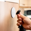 Hand holding a key in front of a round lock on a wooden door