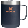 Gobelet bleu foncé avec anse, bord en acier inoxydable argenté et logo Stanley couleur cuivre (lion ailé) sur fond blanc