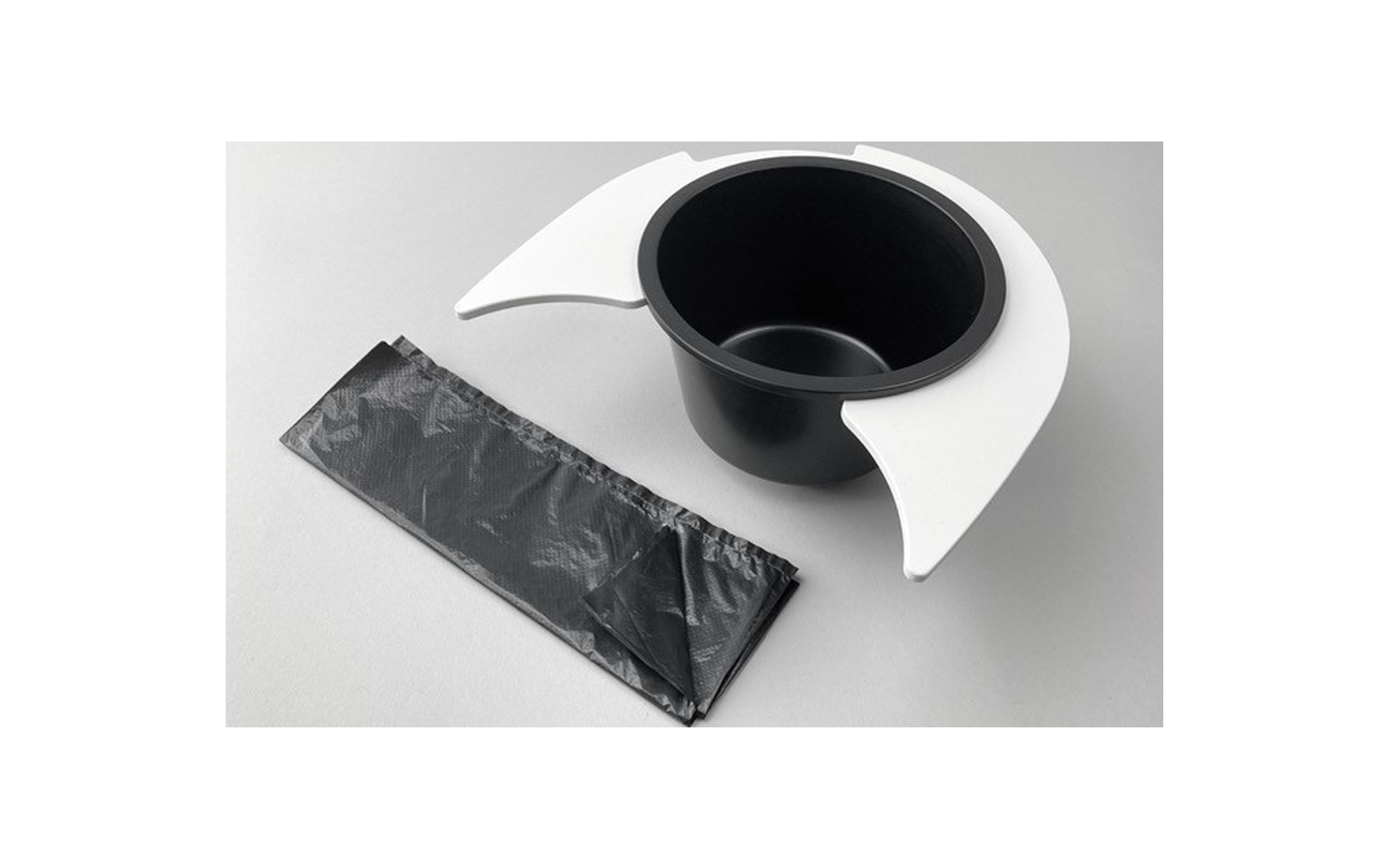 Gobelet noir avec supports blancs et un sac plastique noir emballé sur une surface grise