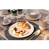 Assiette de petit-déjeuner avec croissant, fruits et fromage, à côté d'une tasse de café, coquille d'œuf, bol et tasses supplémentaires sur une table dressée