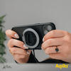 Hand houdt een zwarte instantcamera vast voor een onscherpe groene achtergrond