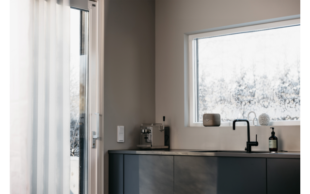 Moderner Küchenbereich mit schwarzer Arbeitsplatte und zwei Wasserhähnen vor einem Fenster