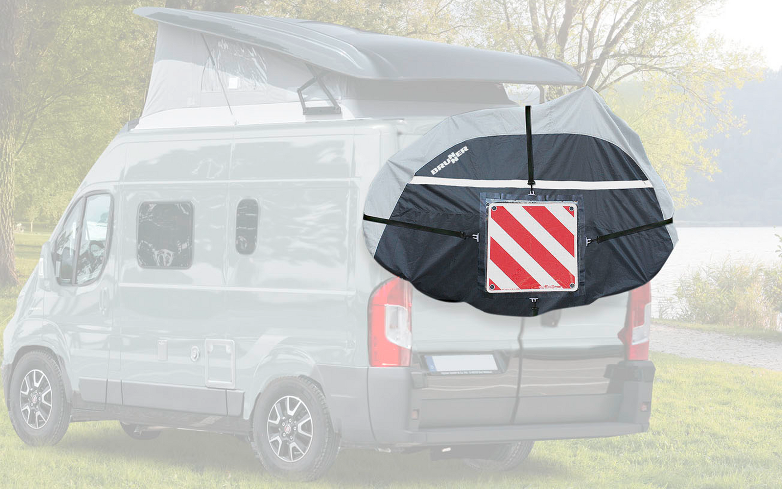 Retro di un camper bianco con portellone posteriore aperto, con una borsa per biciclette nera con un triangolo di segnalazione rosso e bianco attaccato