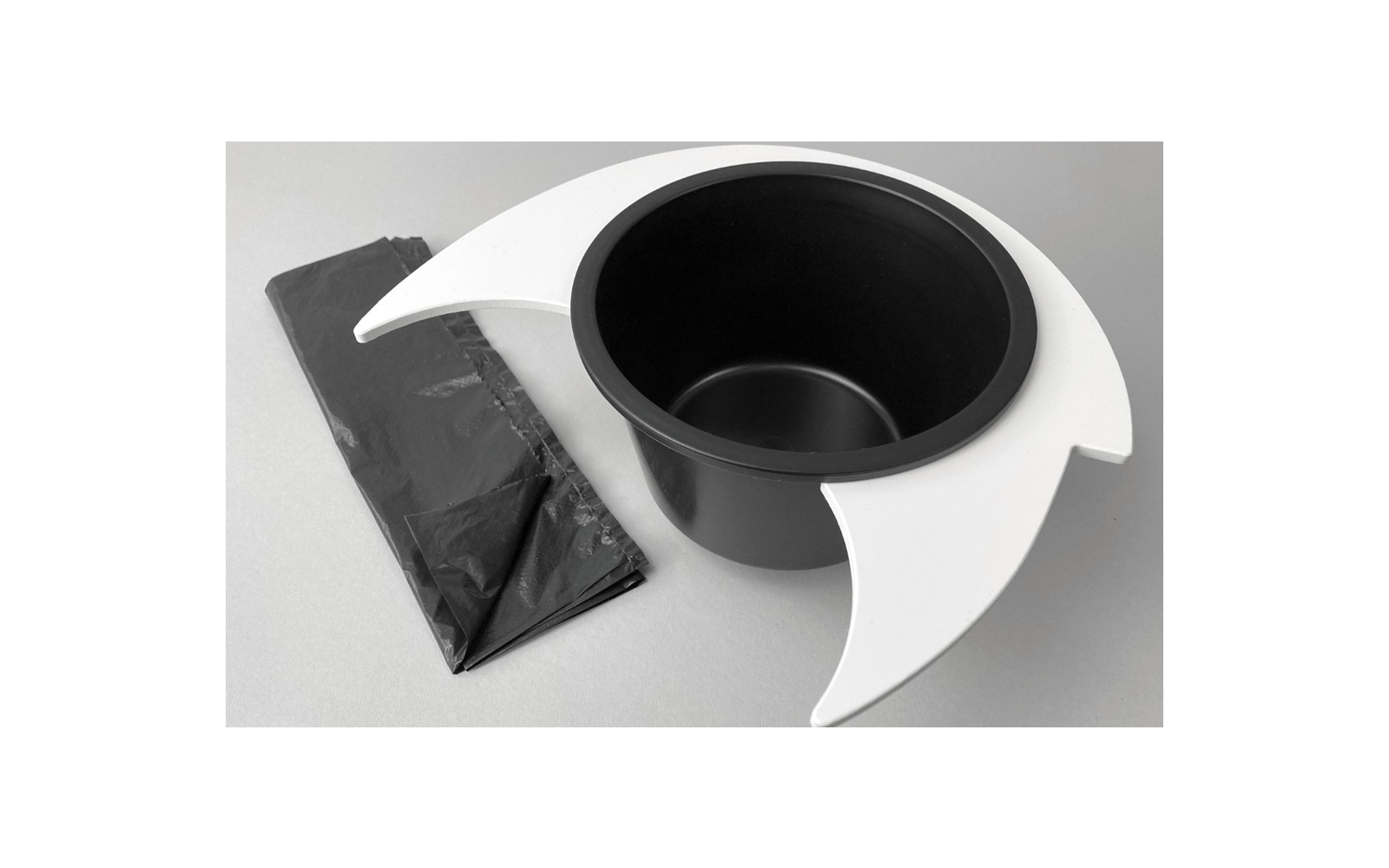 Chapeau noir avec casque blanc et feuille de plastique noire pliée sur une surface grise