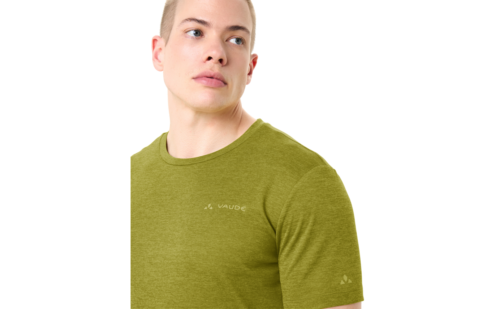 Persoon van borst omhoog, kijkt naar rechts, kort blond haar, draagt een olijfgroen T‑shirt met ronde hals en het "Vaude"-logo op borst en mouw, witte achtergrond