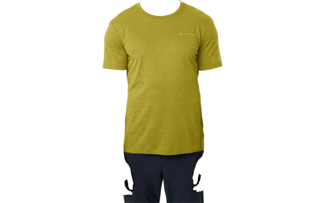 Persoon met kort haar, olijfgroen T-shirt en donkere broek staat recht voor een witte achtergrond, armen langs het lichaam