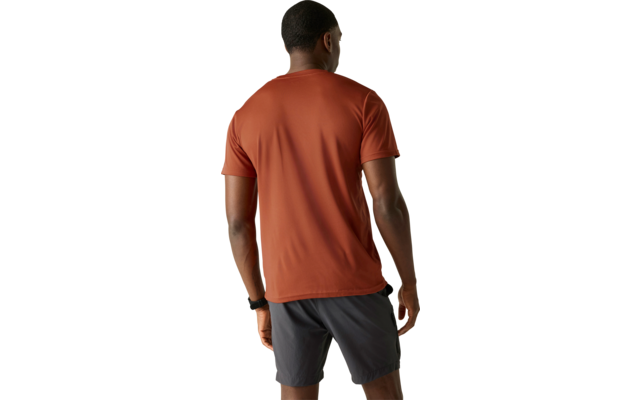 Person von hinten in rostfarbenem kurzärmligen T-Shirt und dunklen Shorts vor hellem einfarbigem Hintergrund