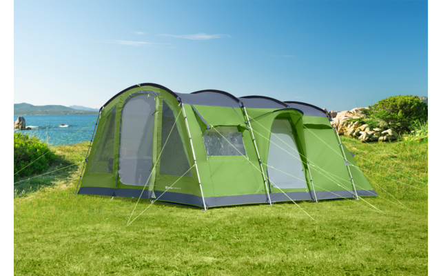 Grünes Zelt auf einer Wiese mit Meer und Bergen im Hintergrund