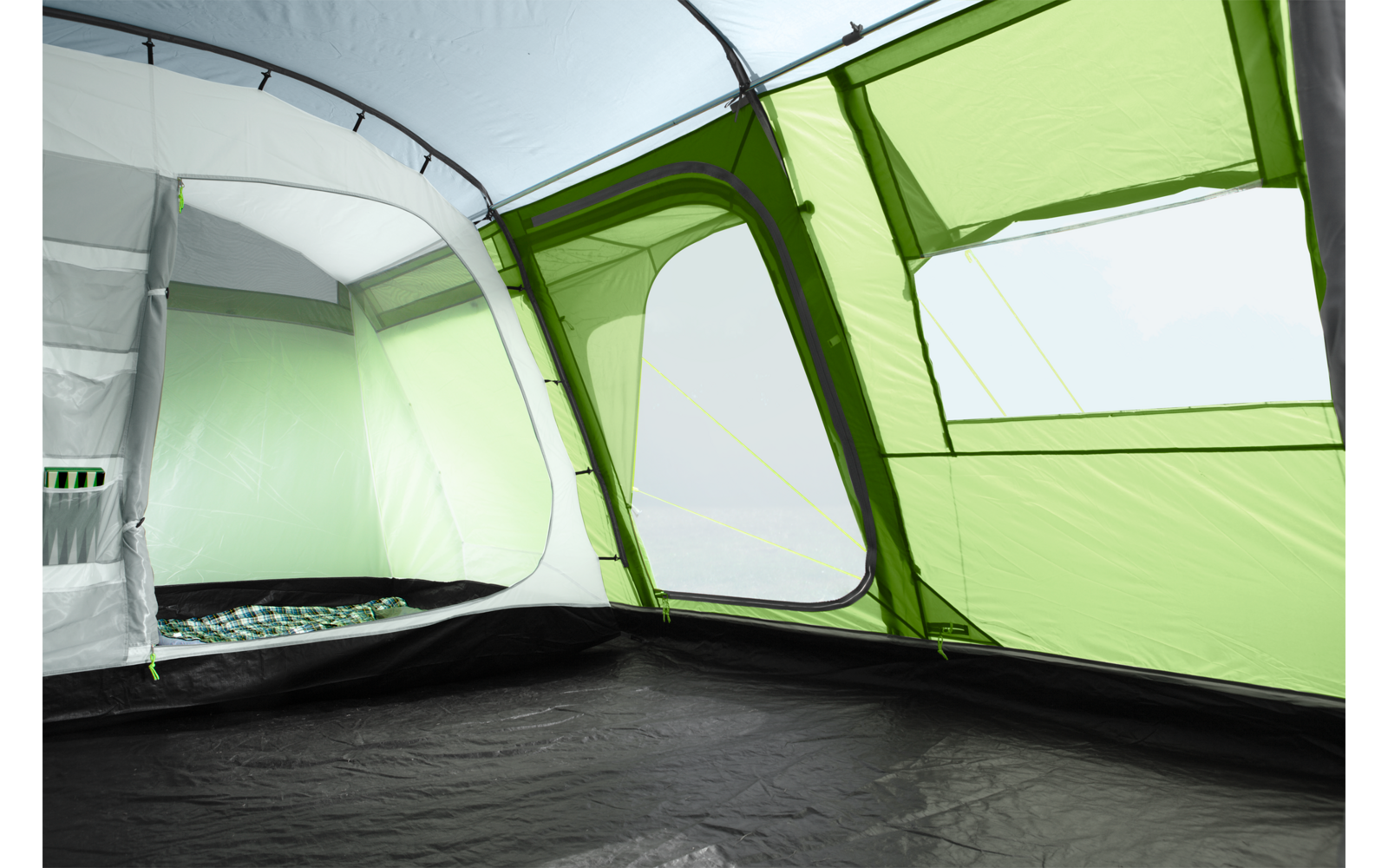 Innenansicht eines grünen Zeltes mit aufgespannten Fenstern und einer Bodenmatte