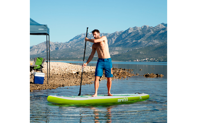Mann auf Stand-Up-Paddle-Board auf ruhigem Wasser mit Bergen im Hintergrund