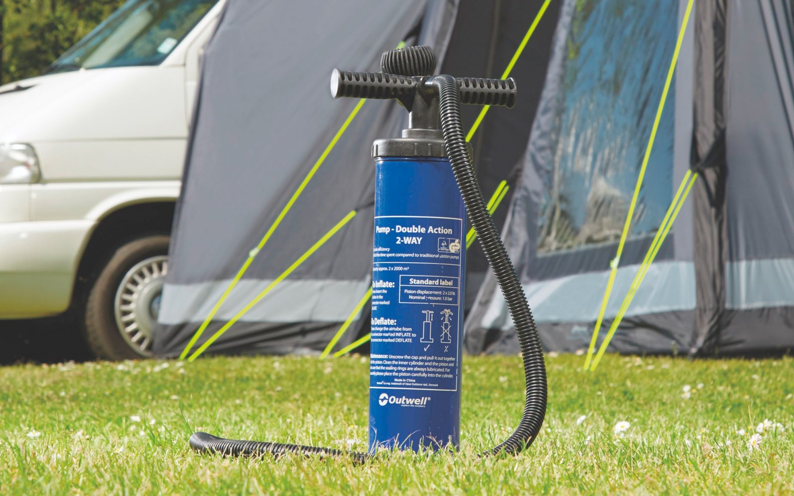 Person in Schutzanzug sprüht im Freien neben Auto und Zelt mit Ausrüstung